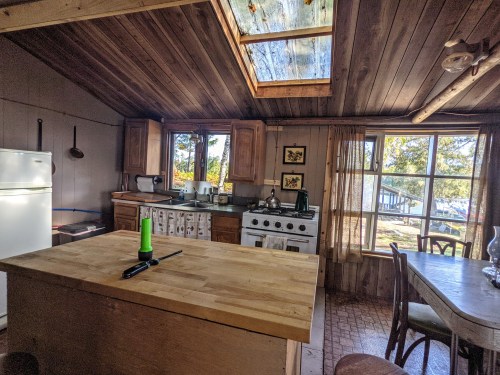 Cozy kitchen with wooden accents, a skylight, and a dining table, featuring a stove and a large island.