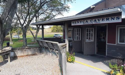 Entrance to Seneca Caverns in Bellevue, Ohio, with trees and a gravel path leading to the building.