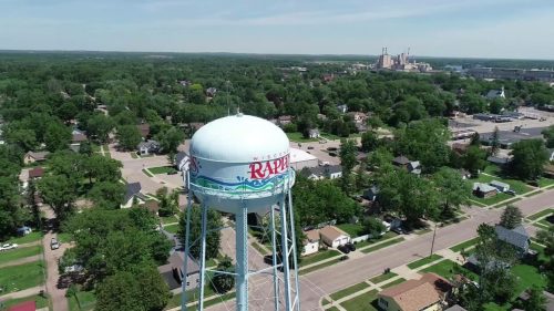 Aerial view of a water tower labeled "RAPID" surrounded by green trees and residential areas.