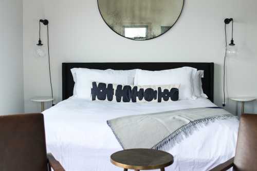 A modern bedroom featuring a large bed with white linens, decorative pillows, and stylish side tables.