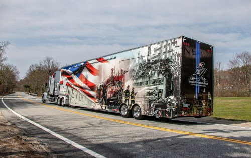 A truck with a patriotic design featuring firefighters and a tribute to 9/11, parked on a rural road.