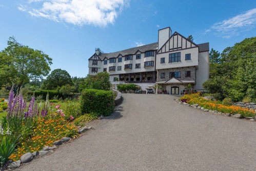 A large, elegant building with a landscaped garden and colorful flowers, set against a blue sky.