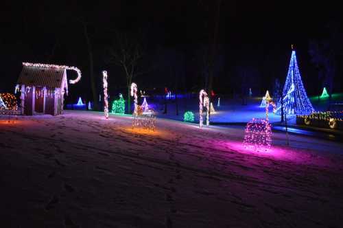 Colorful holiday lights illuminate a snowy landscape, featuring trees and decorative shapes in a festive display.