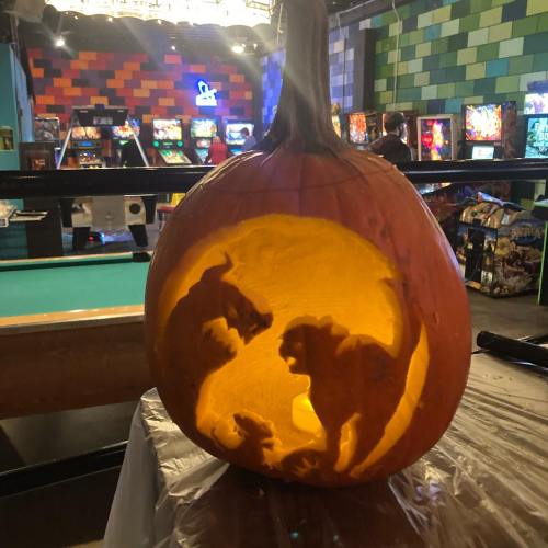A carved pumpkin featuring silhouettes of a dog and a cat against a glowing background.