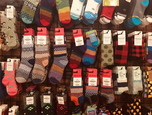 A colorful display of various patterned socks hanging on a rack in a store.