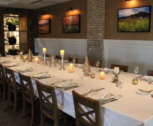 A beautifully set dining table with candles and decorations, surrounded by elegant wall art in a cozy restaurant setting.