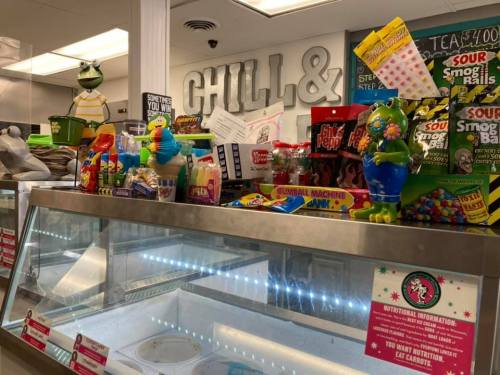 A colorful display of snacks and toys on a counter at an ice cream shop, with a sign reading "Chill &".