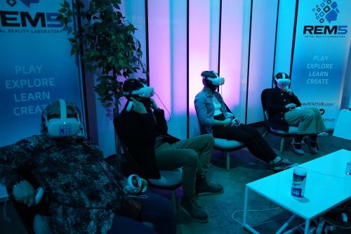Four people wearing VR headsets sit in a modern lab, engaged in virtual reality experiences.