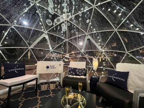 Cozy igloo-style seating area with sparkling lights, plush cushions, and champagne glasses, set for a night out.