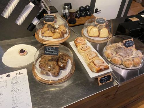 A display of assorted baked goods, including pastries and cakes, under glass domes on a café counter.