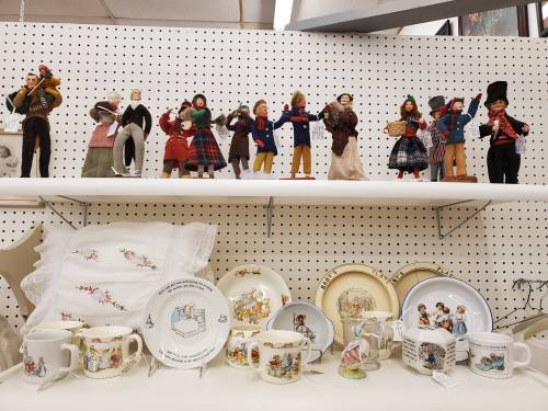 A display of vintage dolls and decorative plates on a shelf, showcasing various designs and characters.