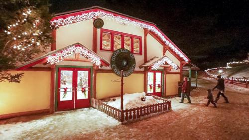 A festive building adorned with colorful lights and snow, with people walking nearby in a winter scene.