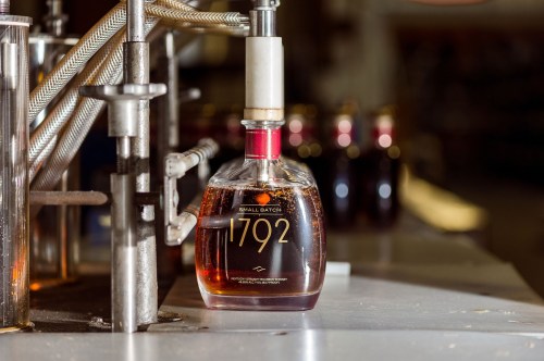A bottle of 1792 Small Batch bourbon on a production line, with blurred bottles in the background.