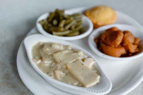 A plate with chicken and dumplings, green beans, sweet potatoes, and a cornbread muffin.