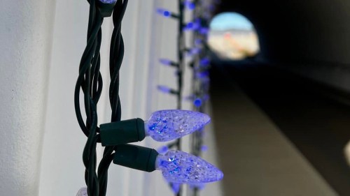 Close-up of blue decorative lights on a wire, with a blurred tunnel in the background.