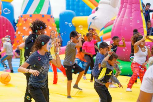 Children playing joyfully on a colorful inflatable playground, surrounded by bubbles and vibrant structures.