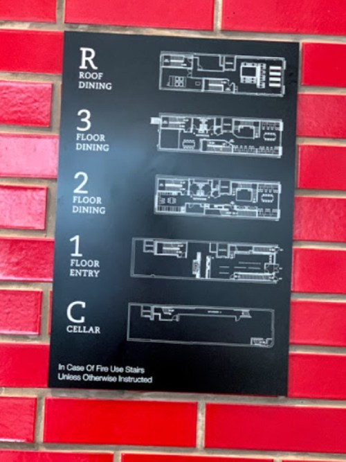 Sign displaying a building's floor plan, including roof dining, multiple dining levels, entry, and cellar.