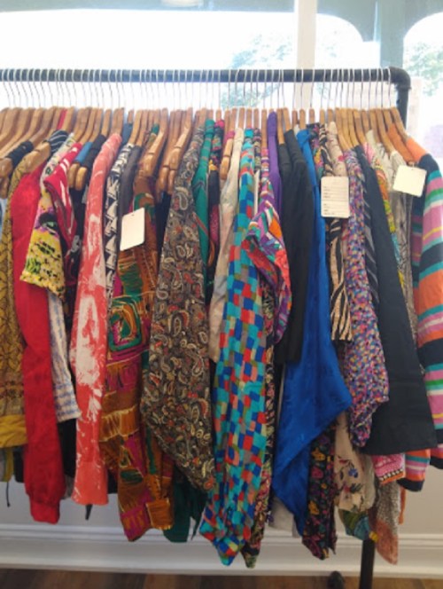 A colorful display of various patterned shirts hanging on a rack.