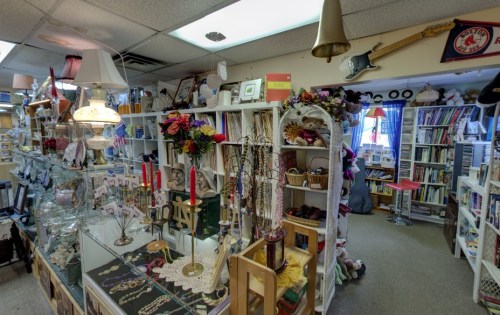 A cozy shop filled with various decorative items, including lamps, flowers, and books, creating a charming atmosphere.
