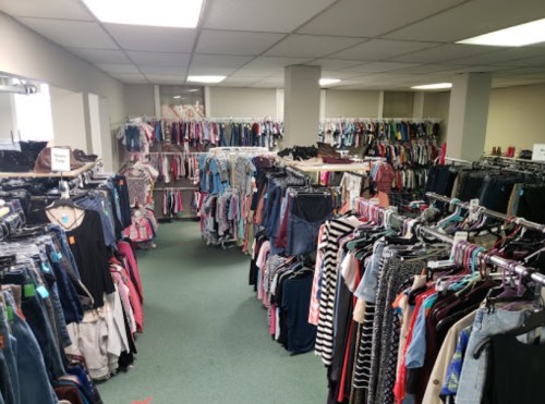 A spacious clothing store with racks of various clothes organized in rows, featuring a mix of styles and colors.