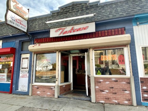 Exterior of a restaurant named "Tastease," featuring a red awning and a welcoming entrance.
