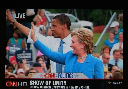 Barack Obama and Hillary Clinton wave to a crowd during a campaign event in New Hampshire, with a CNN broadcast overlay.