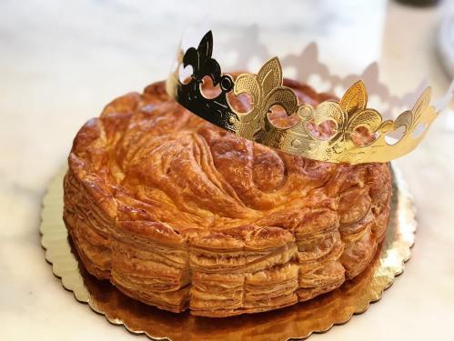 A golden crown sits atop a flaky, round pastry on a decorative plate.