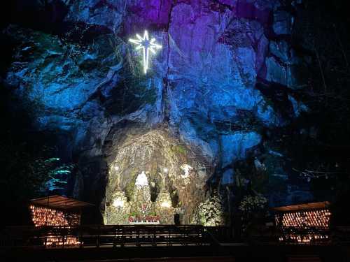 A illuminated cave with a star decoration, surrounded by colorful lights and floral arrangements.