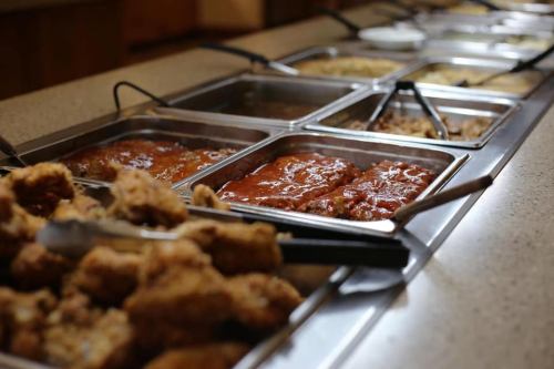 A buffet spread featuring various dishes in metal trays, including fried chicken and sauces.
