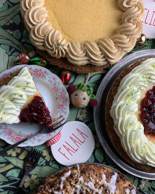A festive display of various cakes, including a slice topped with cherry and whipped cream, on a decorative table.