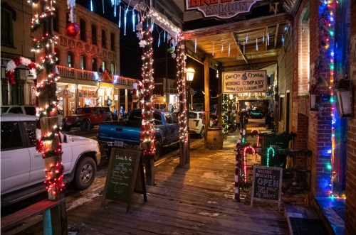 A festive street scene at night, adorned with colorful lights and holiday decorations on a wooden walkway.