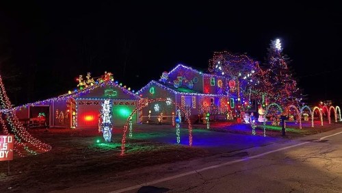 A brightly lit house decorated with colorful Christmas lights, featuring festive displays and a decorated tree.
