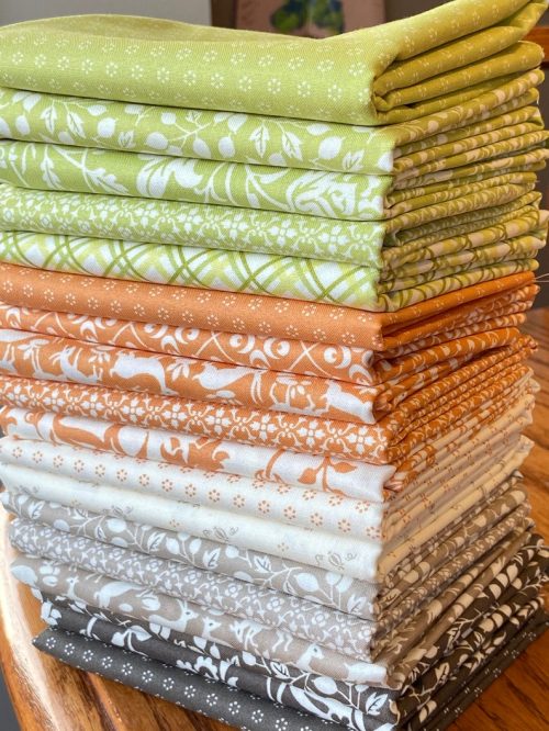 A stack of neatly folded fabric squares in various shades of green, orange, cream, and brown with floral patterns.