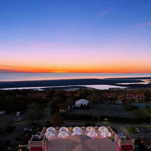 A serene sunset over a calm lake, with colorful skies and distant hills, viewed from a high vantage point.