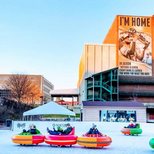 A winter scene with people on colorful snow tubes, a large building with a sign reading "I'M HOME" in the background.