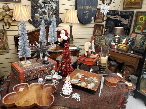 A cozy vintage shop display featuring holiday decorations, antique items, and festive decor on a wooden table.