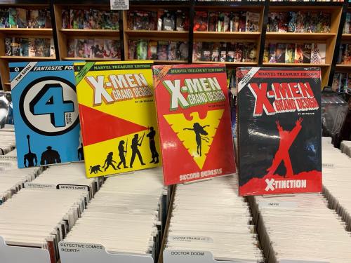 Four comic books displayed on a shelf, featuring "Fantastic Four" and various "X-Men" titles in vibrant covers.