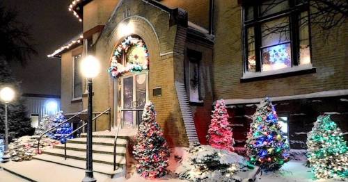 A snow-covered building decorated with colorful Christmas lights and trees, illuminated at night.