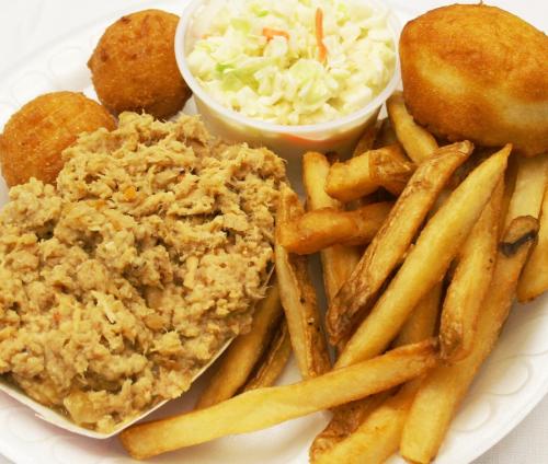 A plate of pulled pork, coleslaw, cornbread muffins, and French fries.