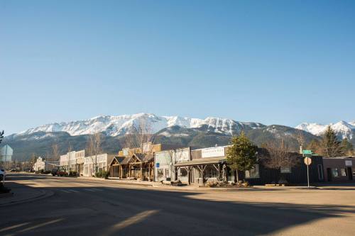 A quiet street in a small town with snow-capped mountains in the background under a clear blue sky.