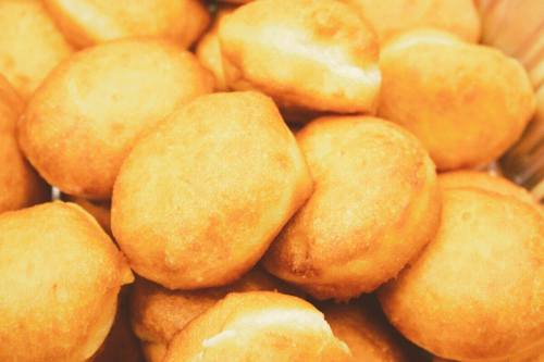 A close-up of golden-brown, fluffy fried dough balls stacked in a basket.