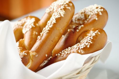 A basket of freshly baked pretzels topped with coarse salt, resting on a white cloth.