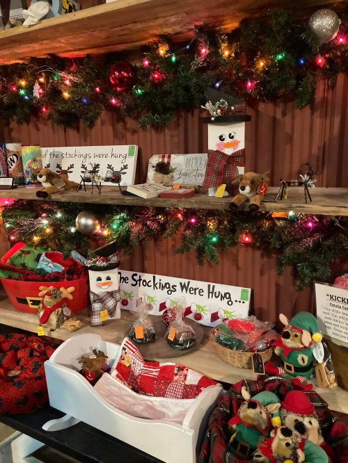 A festive display with holiday decorations, stockings, and plush toys, adorned with lights and greenery.