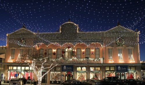 A beautifully decorated building adorned with festive lights and wreaths, glowing under a starry night sky.