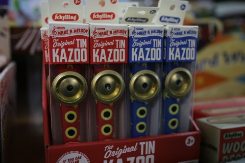 A display of colorful tin kazoos in red and blue packaging, labeled "The Original Tin Kazoo."