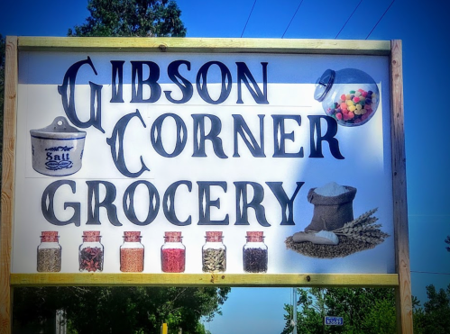 Sign for "Gibson Corner Grocery" featuring jars of spices and a bowl of salt, with colorful candies in a jar.