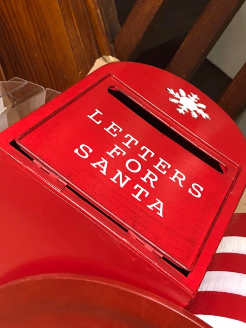 A red mailbox with the words "Letters for Santa" and a snowflake design, placed indoors.