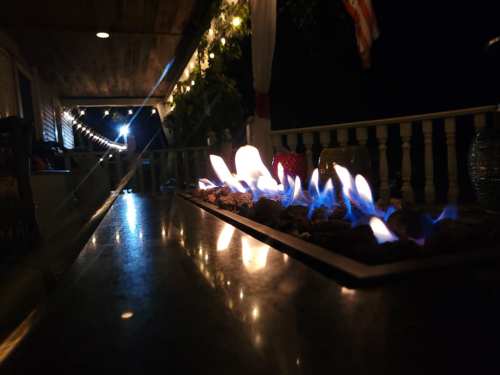 A close-up of a fire feature with blue flames, set on a table, illuminated by soft lights in the background.