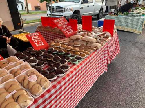 A table at a market displaying various whoopie pies and baked goods, with prices on red signs.