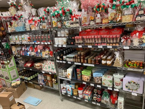 A colorful display of holiday-themed food items and gifts on shelves, including cookies, chocolates, and preserves.